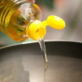 A person pouring kitchen soul oil into a pan